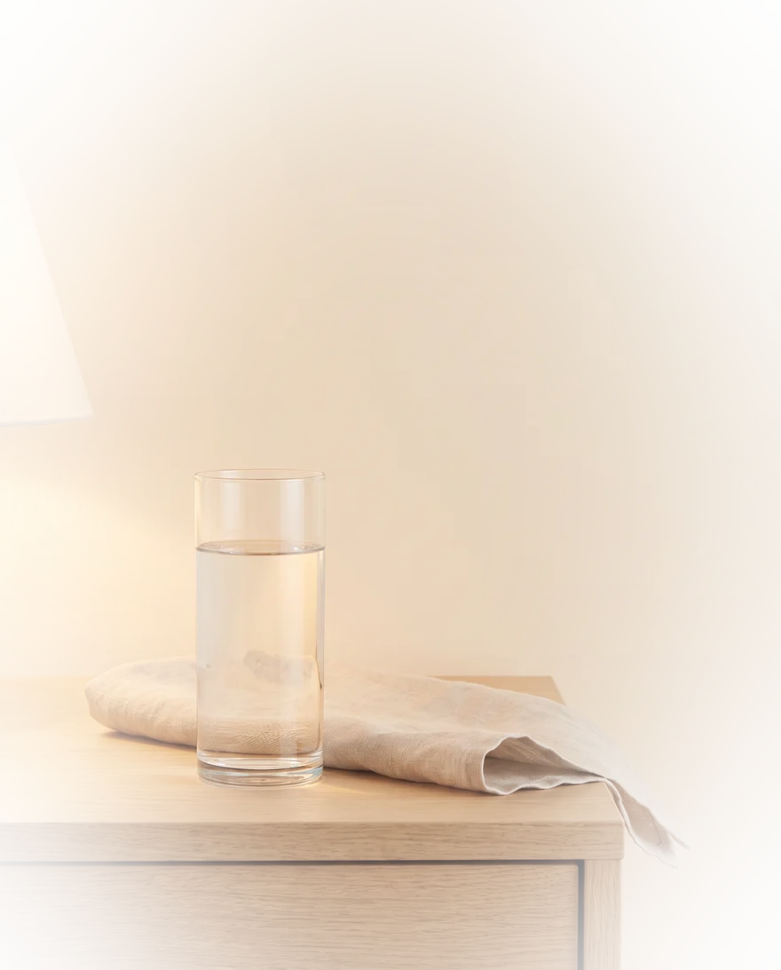 Glas water op een nachtkastje in warm avondlicht