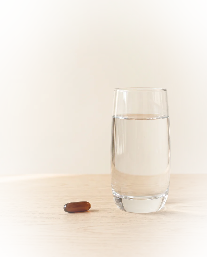 Capsule naast een glas water in het ochtendlicht
