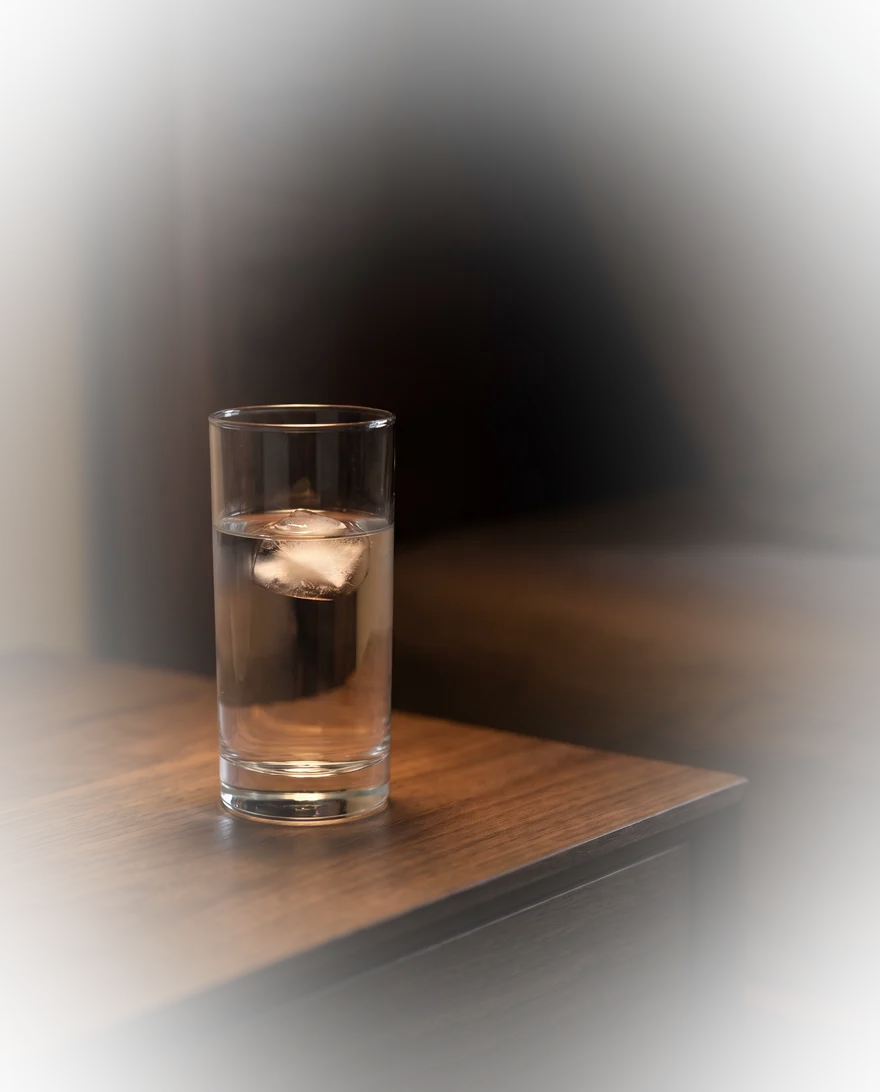 Glas water op een houten nachtkastje in warm avondlicht