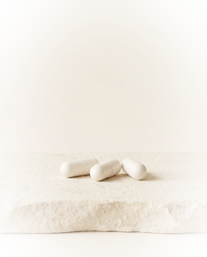 Drie witte vegan capsules op een lichte steen